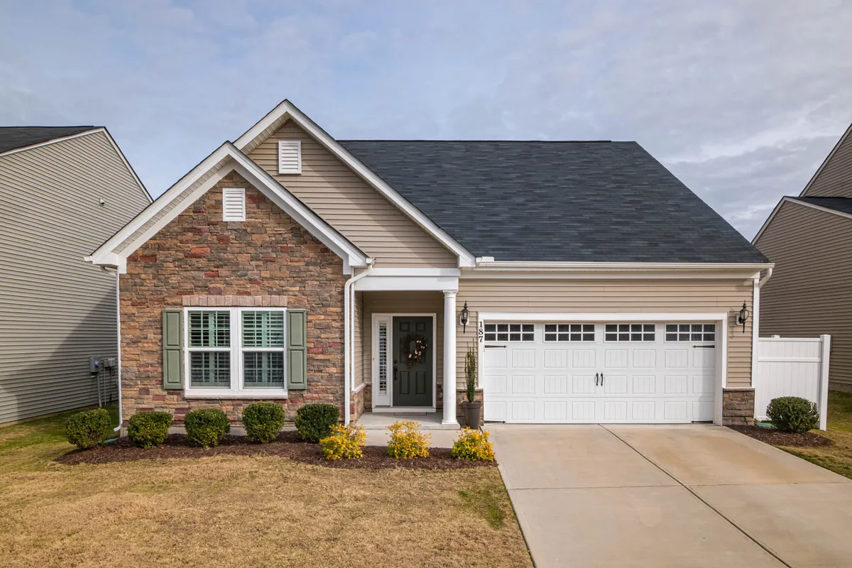 Exterior of a home with a stone-and-siding facade and green shutters