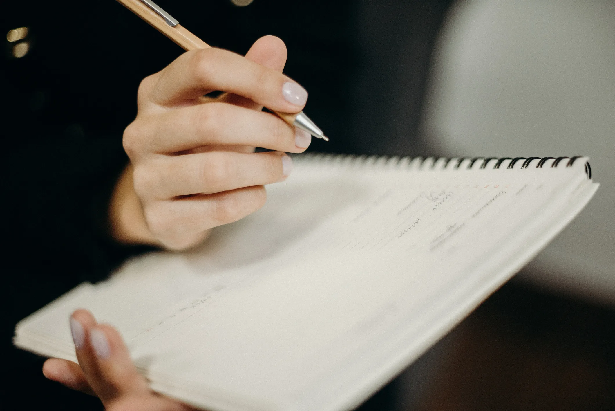 Close-up of a hand writing an intention in a notebook
